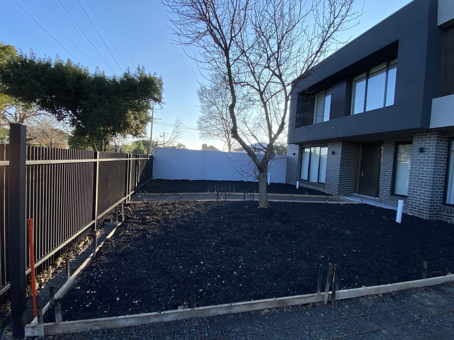 Black aluminium blade fencing along the side of a front garden at Ashburton while the garden was being formed up, with the pale grey VogueWall across the far end.