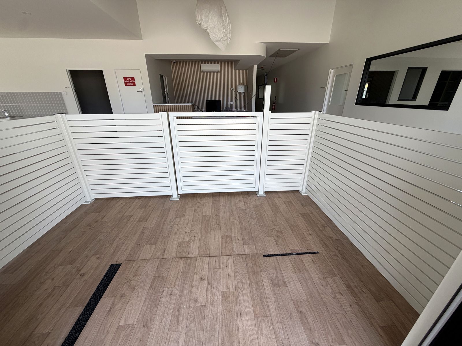 The white aluminium slat child-safe entry inside the Craigieburn childcare centre, with its slatted gate closed.