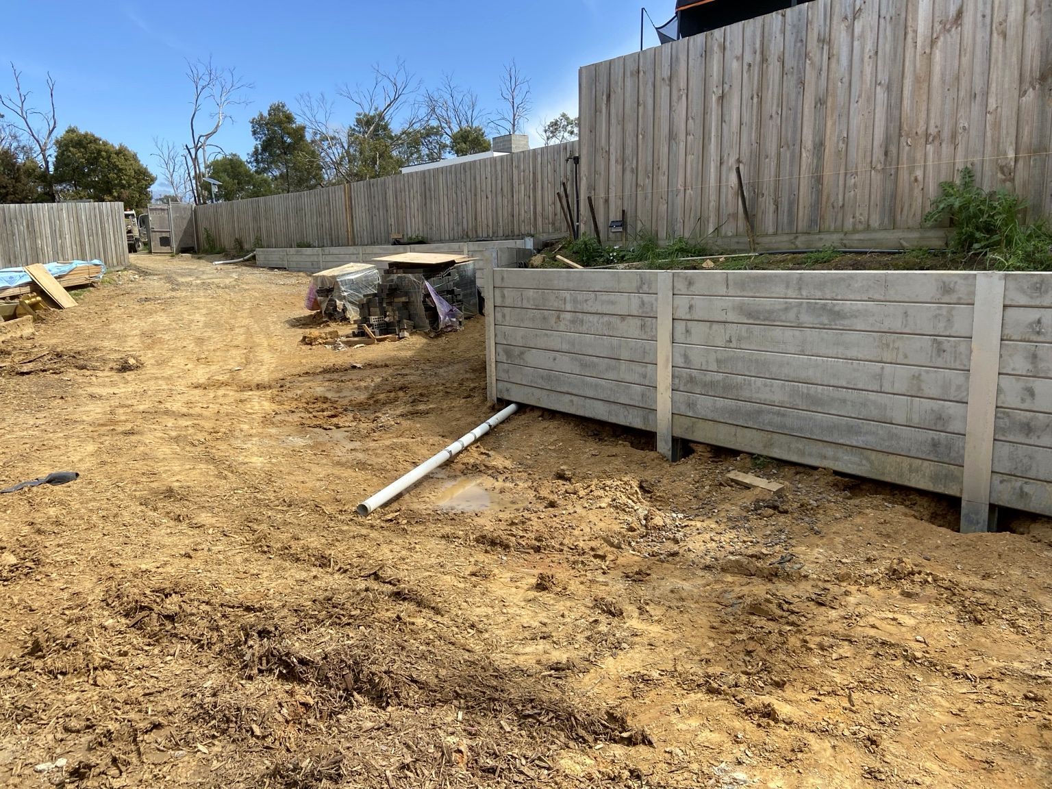 A run of concrete sleeper retaining wall on steel posts holding a raised bed above cleared ground, Mount Eliza.