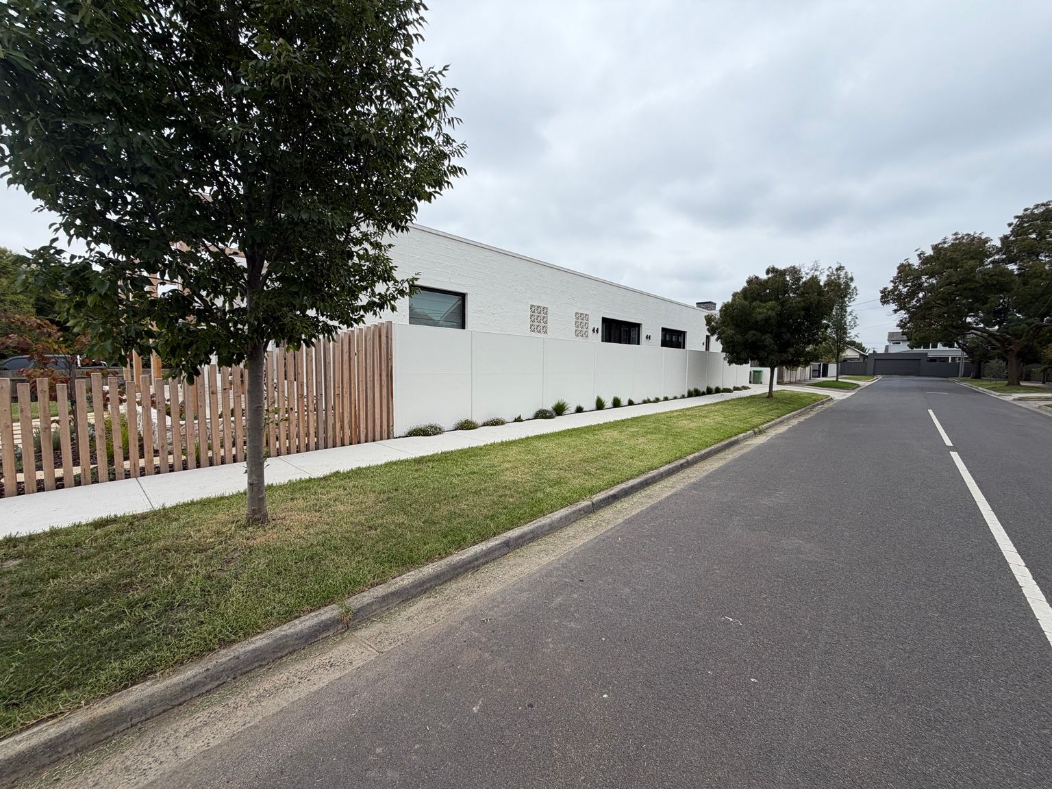 White SlimWall along a street boundary at Reservoir, with hardwood batten fencing at the corner.