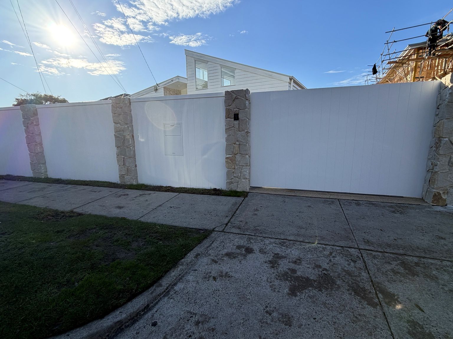 Seaford frontage: white EstateWall with stone-clad posts and a closed sliding gate made to match the wall, an intercom set into the post beside it.
